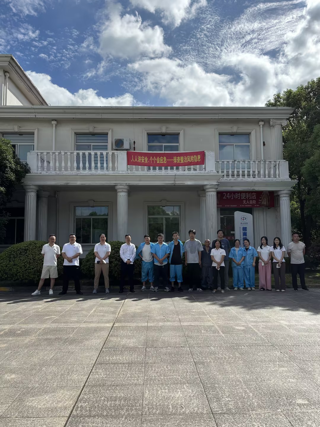 全体员工在公司门前消防疏散集合点列队合影,背景悬挂安全生产宣传横幅